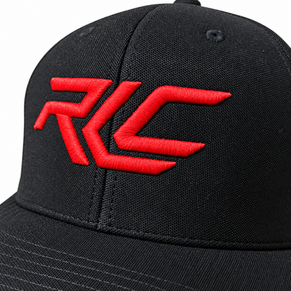 A close-up of a black baseball cap featuring a bold red embroidered 'RLC' logo on the front panel, set against a plain white background.