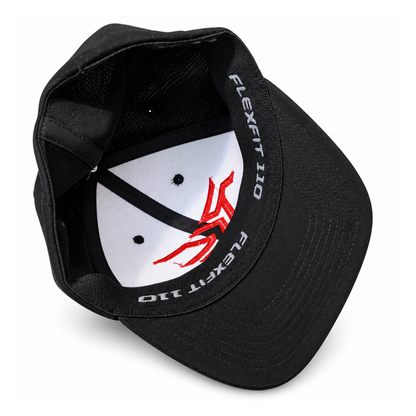 Black structured baseball cap shown from an angled top view, featuring a white inner crown with a red graphic logo and white 'FLEXFIT 110' text printed along the inner band.